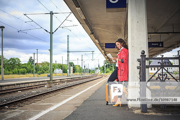 Deutschland  junge Frau am Bahnhof Sonneberg  Zeitung lesen