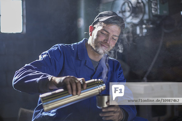 Mechanic in workshop having coffee break