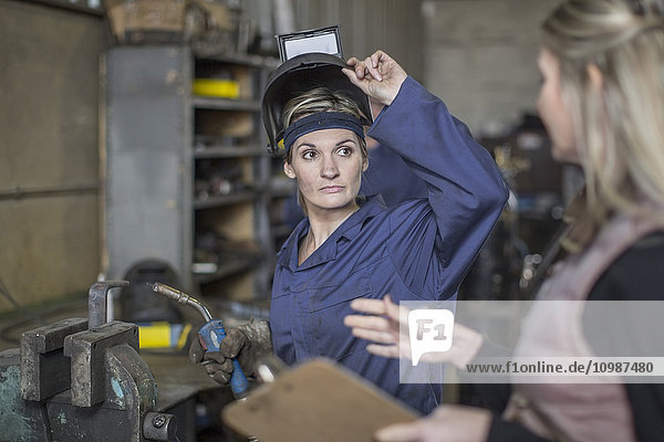 Frau im Gespräch mit Mechanikerin in der Werkstatt