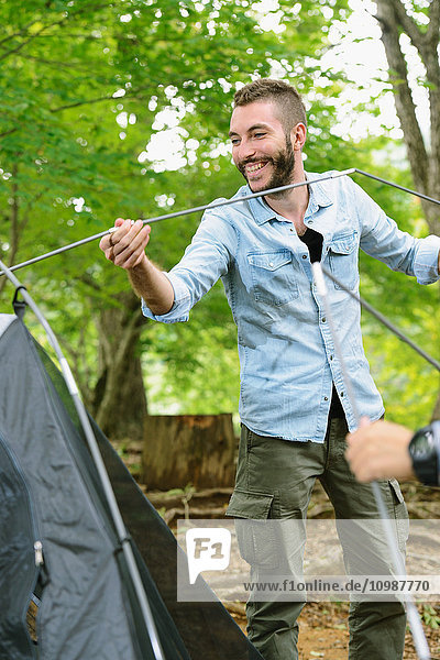 Caucasian man putting up a tent at a camp site