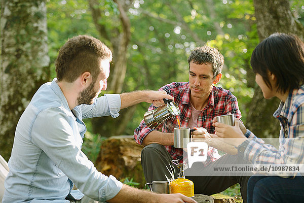 Multi-ethnic group of friends having coffee at a camp site