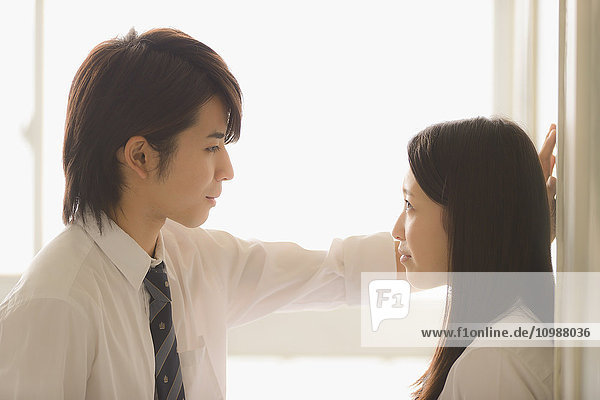 Japanische Gymnasiasten in einem romantischen Moment im Schulkorridor
