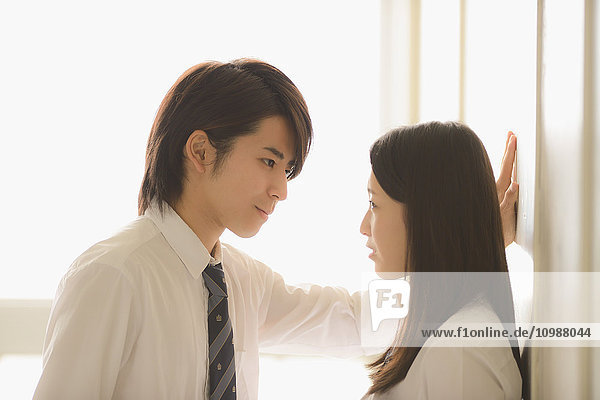 Japanische Gymnasiasten in einem romantischen Moment im Schulkorridor