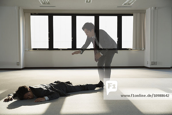 Ein junger japanischer Geschäftsmann liegt tot auf dem Boden eines leeren Büros