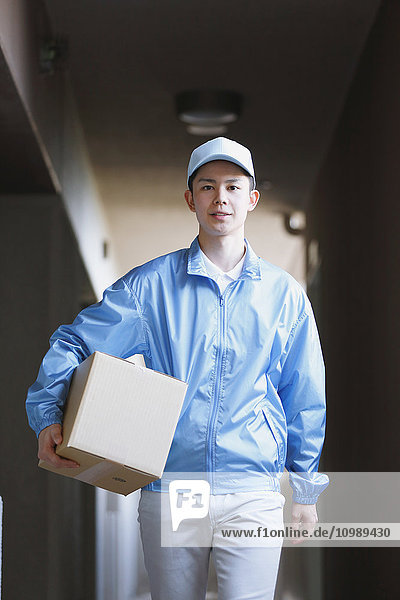 Young Japanese delivery man with box