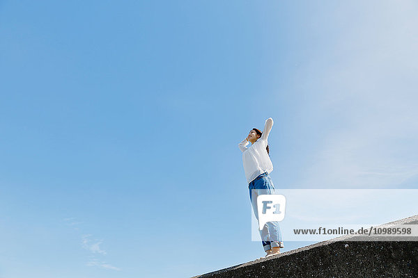 Junge Japanerin an einer Betonmauer am Meer stehend