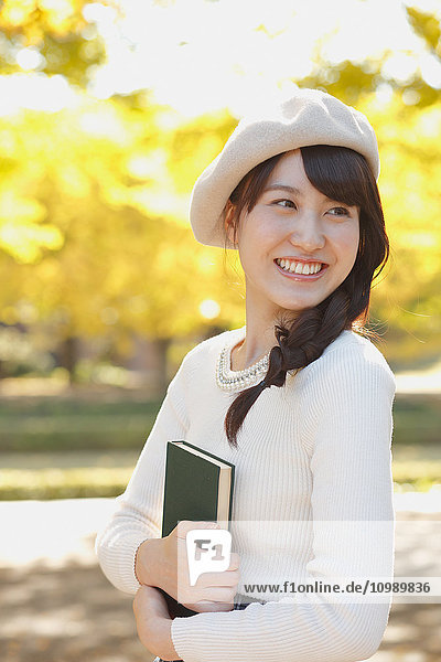 Young Japanese woman with book in a city park