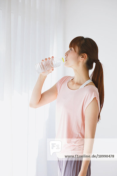 Junge Japanerin trinkt Wasser nach einer Yogapraxis