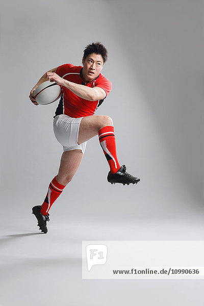 Porträt eines japanischen Rugbyspielers  der mit einem Ball läuft