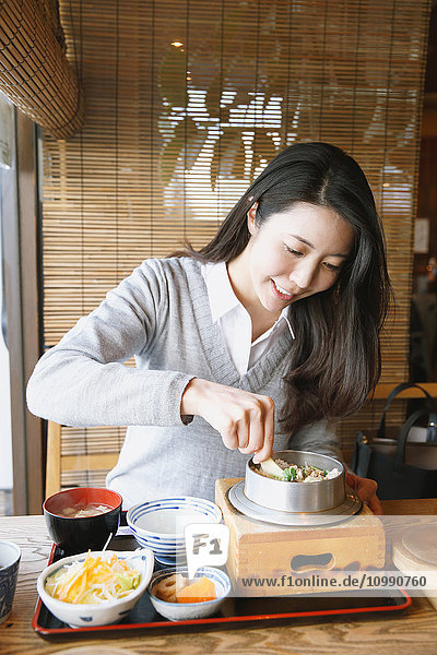 Junge attraktive Japanerin beim Essen im Restaurant