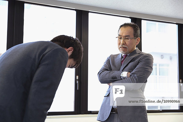 Junger japanischer Geschäftsmann wird von seinem Chef bewertet