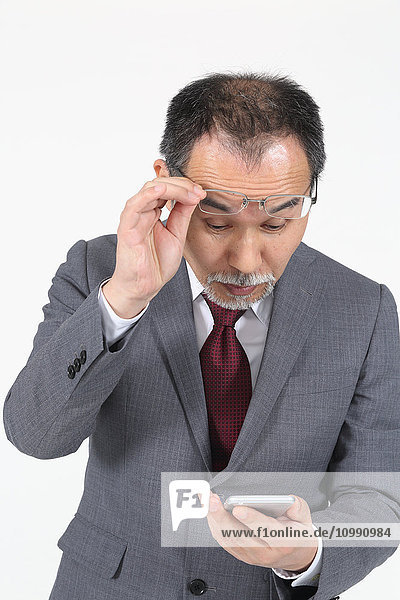 Japanese senior businessman having issues with Smartphone