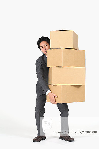 Junger japanischer Geschäftsmann trägt Kisten