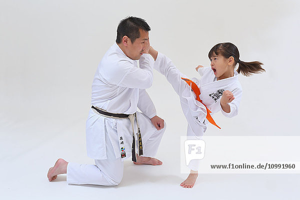 Japanese kid in karate uniform training with teacher on white background