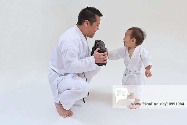 Japanisches Kind in Karate-Uniform Training mit Lehrer auf weißem Hintergrund