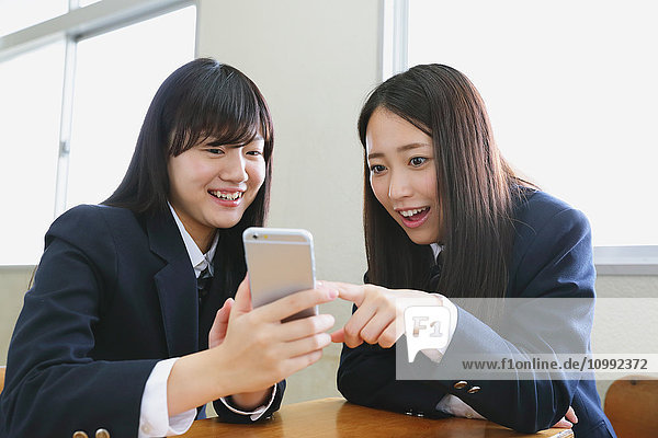 Japanische Gymnasiasten mit Smartphone im Klassenzimmer