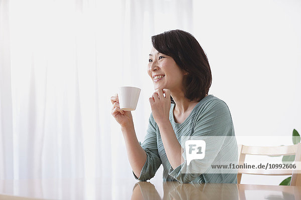 Senior Japanese woman having coffee in the living room