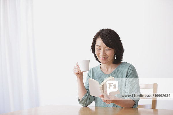 Senior Japanese woman having coffee in the living room