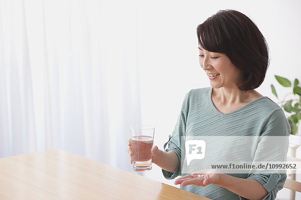 Senior Japanese woman taking pills in the living room