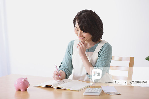 Senior Japanese woman doing accounting in the living room