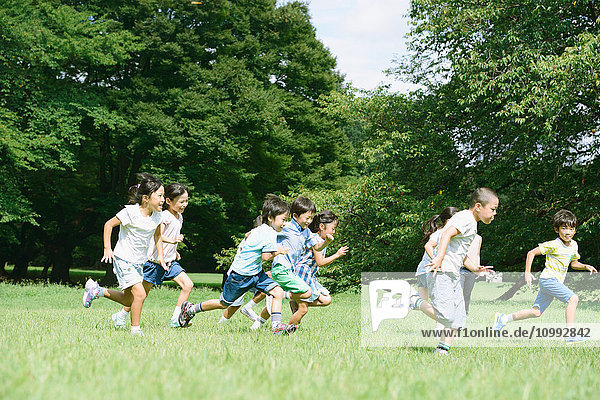 Japanische Kinder laufen in einem Stadtpark
