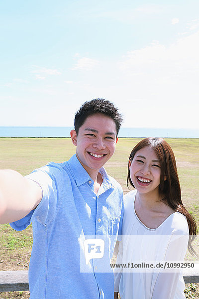 Young Japanese couple taking selfie by the sea