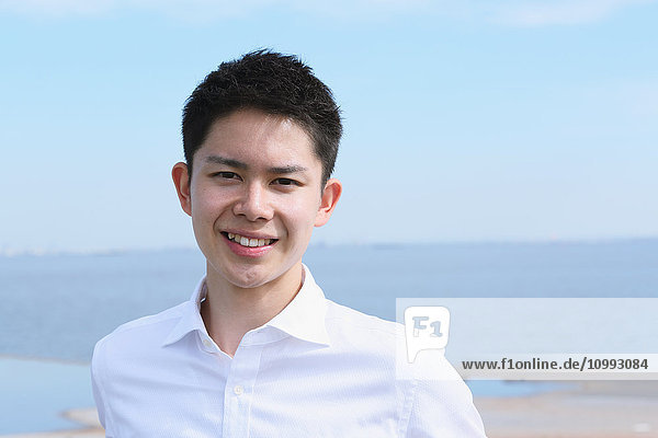 Portrait of young Japanese man by the sea