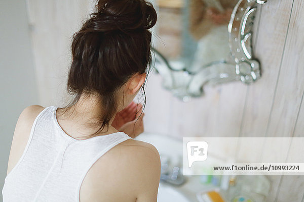 Junge attraktive japanische Frau wäscht ihr Gesicht im Badezimmer