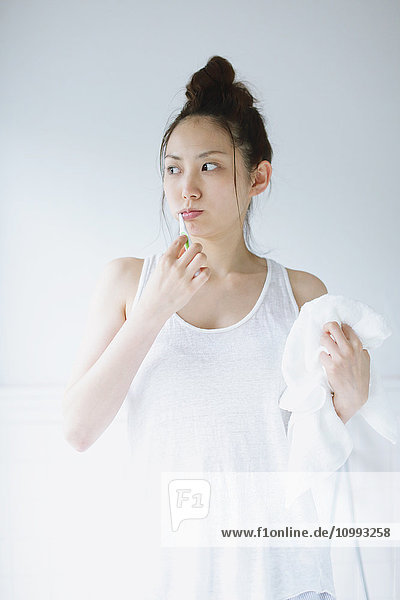 Junge attraktive japanische Frau beim Zähneputzen im Badezimmer