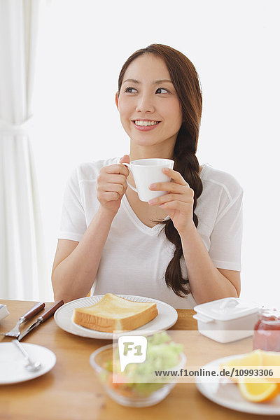 Junge attraktive Japanerin beim Frühstück zu Hause