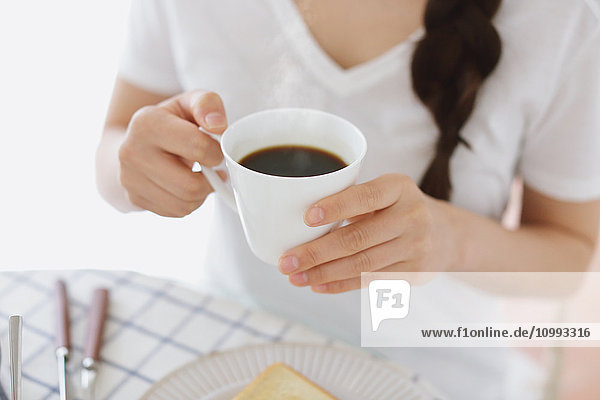 Young attractive Japanese woman having breakfast at home