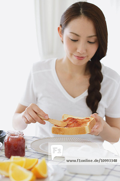 Young attractive Japanese woman having breakfast at home