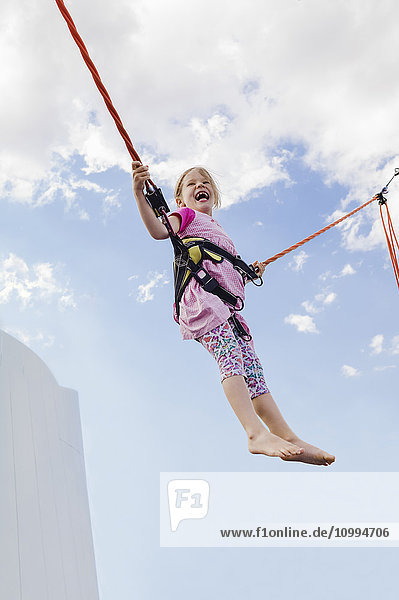 6-jähriges Mädchen springt mit einem Bungee-Trampolin an einem sonnigen Tag  Deutschland