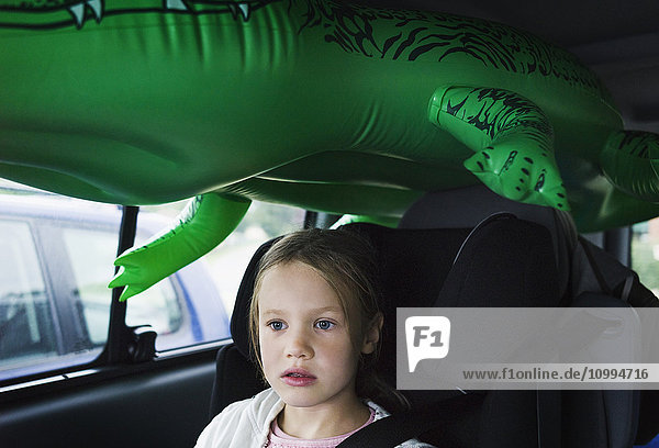 6-jähriges Mädchen  das mit einem grünen Plastikkrokodil im Auto sitzt  Deutschland