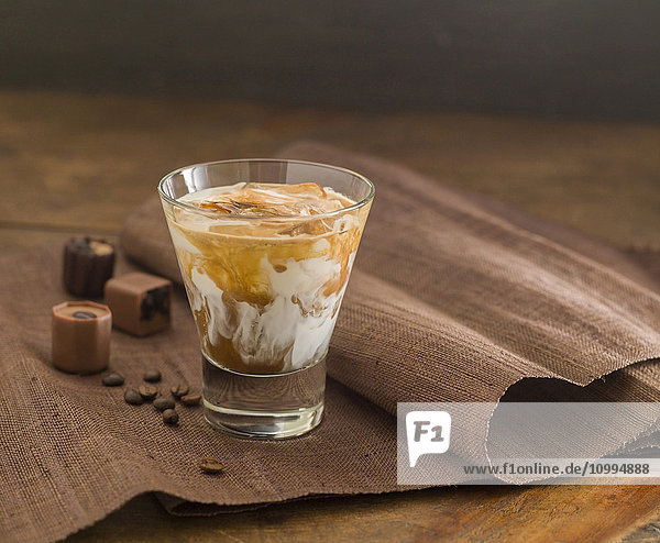 Eiskaffeegetränk im Glas mit Schokolade und Kaffeebohnen an der Seite