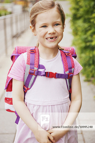 5 Jahre altes Schulmädchen mit rosa Schultasche lächelnd mit fehlenden Zähnen