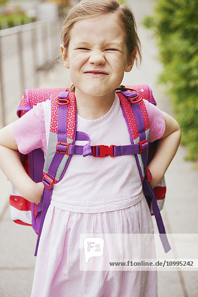 5 Year Old Schoolgirl with Pink School Bag Making Faces with Hands on Hips