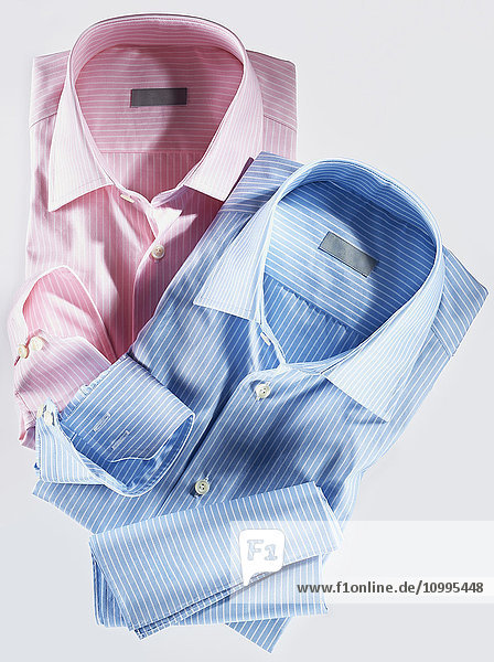 Zwei Hemden  rosa und blau  auf weißem Hintergrund  Studioaufnahme