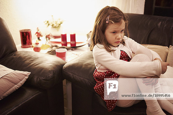 6-jähriges Mädchen sitzt zu Weihnachten auf einem Sofa und sieht traurig aus  Deutschland