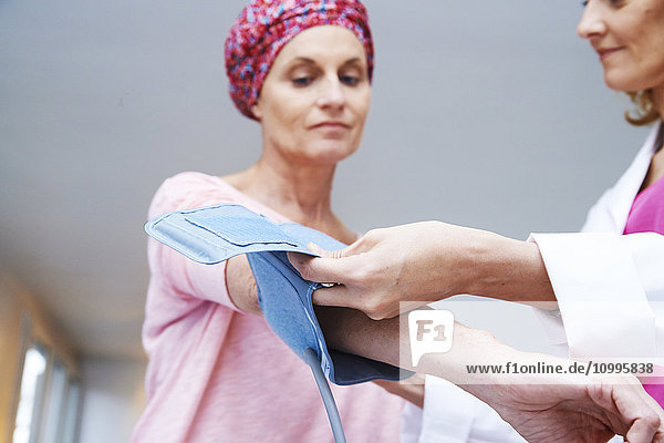 Ein Arzt misst den Blutdruck einer Frau  die an Krebs leidet.