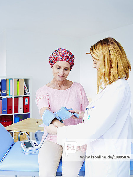Doctor measuring blood pressure of a woman suffering from cancer.