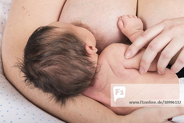 Mother breast feeding 2-week-old baby.