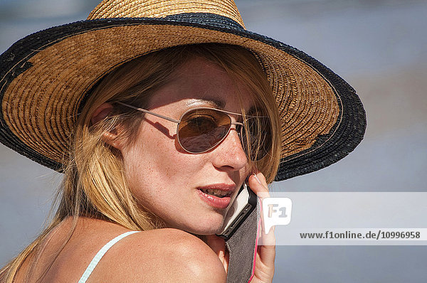 Young woman telephoning on the beach.
