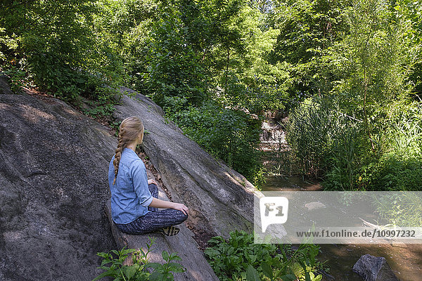 Woman sitting on stone in forest