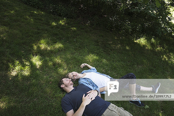 Couple lying on grass in forest