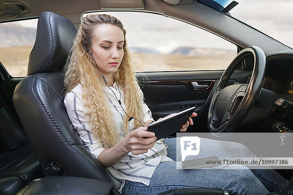 Woman sitting in car and using tablet
