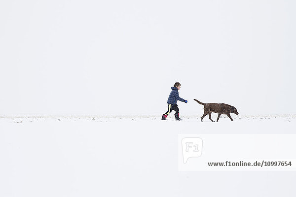 Boy (6-7) walking with dog in winter
