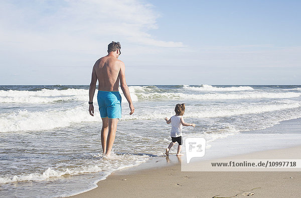 Vater mit Tochter (18-23 Monate) beim Spaziergang am Strand