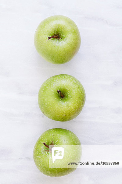 Draufsicht auf drei Äpfel auf einem Marmortisch