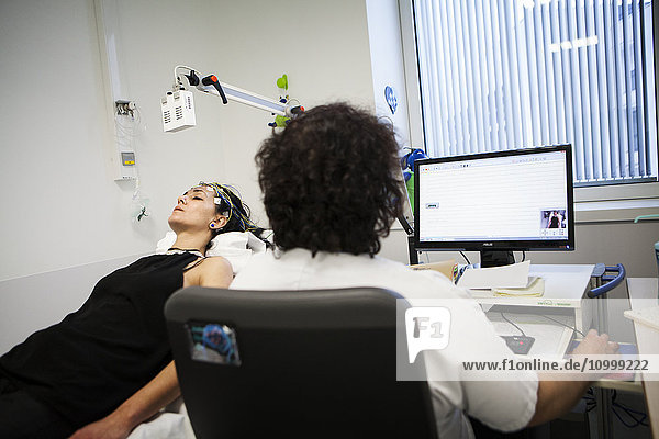 Reportage in einer funktionellen neurologischen Erkundungseinheit. Epilepsie-Screening und Folgeberatung. Die Patienten machen ein Video-EEG (Elektroenzephalogramm)  bei dem sie verschiedenen akustischen und visuellen Reizen ausgesetzt werden. Die Muster werden anschließend von einem Neurologen analysiert. Patient und Krankenschwester während der Untersuchung.